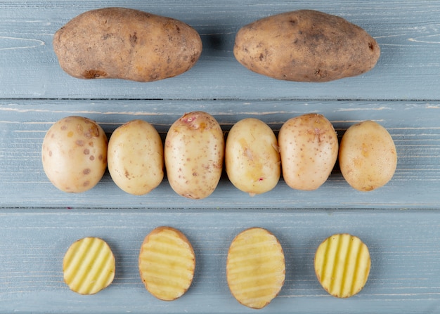 Free photo close up view of pattern of whole and sliced potatoes on wooden background 2