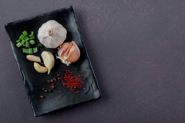 Free Photo close-up view of plate of vegetables as garlic cut scallion with spices on maroon background with copy space