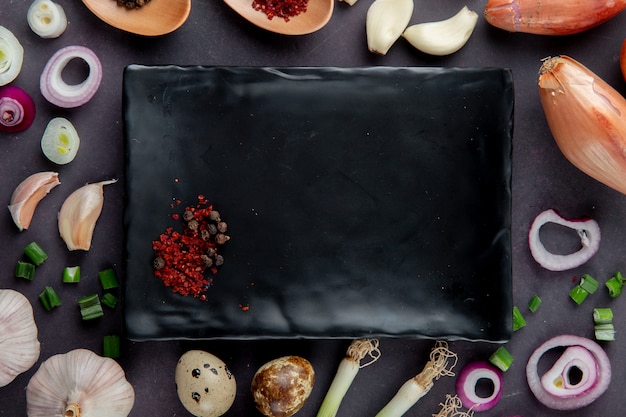 Free photo close-up view of plate with spices and vegetables around as onion garlic egg scallion on maroon background