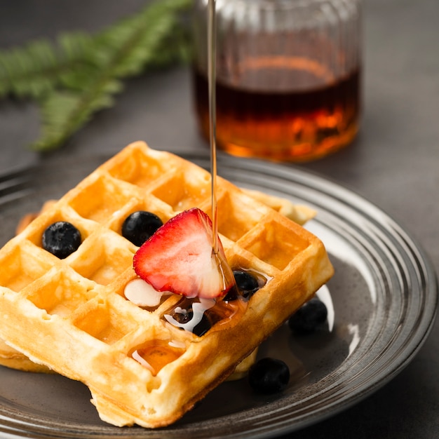 Close-up view of pouring maple syrup on waffle