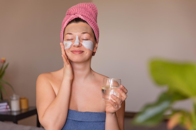 Free Photo close up view of smile woman with mask on face at home with glass water