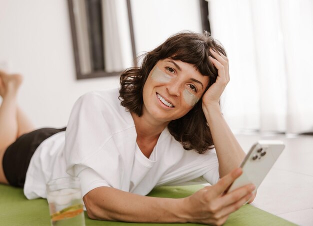 Close up view of smiling woman with gel green patches with phone