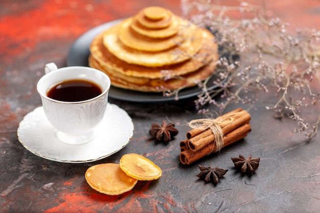 Close up view of tasty breakfast with pluffy pancakes ad a cup of tea next to cinnamon lime