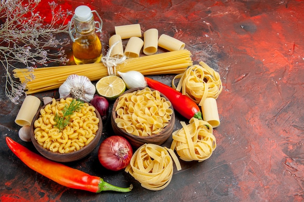 Free Photo close up view of uncooked pastas oil bottle and foods for dinner preparation on mixed color table 