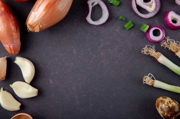 Close-up view of vegetables as garlic cloves shallot onion egg on maroon background with copy space