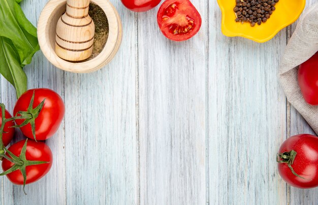 Close-up view of vegetables as tomato spinach with black pepper garlic crusher on wooden table with copy space