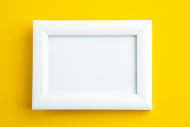 Close up view of white empty picture frame on yellow with free space