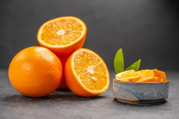 Close up view of whole and chopped fresh orange on dark table