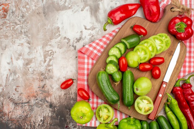 Close up view of whole and chopped fresh vegetables on wooden cutting board