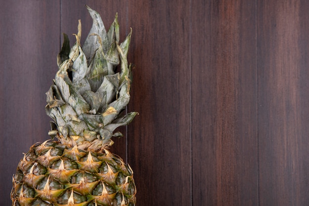 Free photo close up view of whole pineapple on wooden wall with copy space