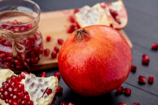 Free photo close up view of whole pomegranate and pomegranate piece with berries on black wall