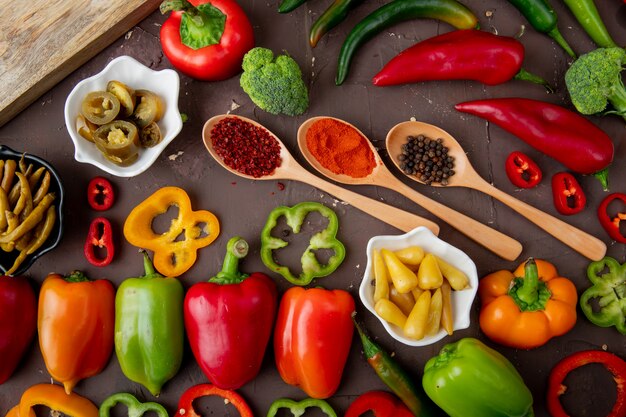 Close-up view of whole, salted, sliced peppers with broccoli and spices