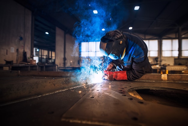 Close up view of worker welding metal construction in industrial workshop