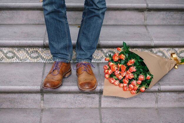 Close-up of vintage shoes with purple laces and a bouquet of roses