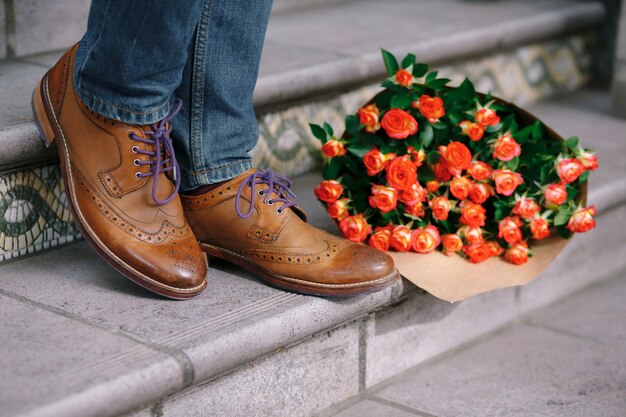 Close-up of vintage shoes with purple laces and a bouquet of roses