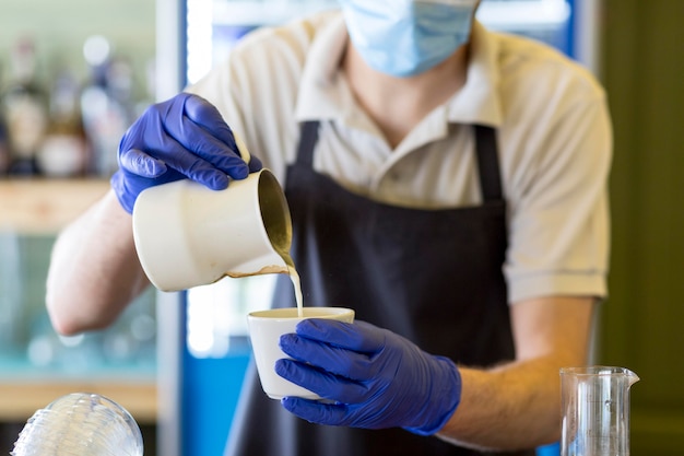 Close-up waiter with gloves preparing coffee