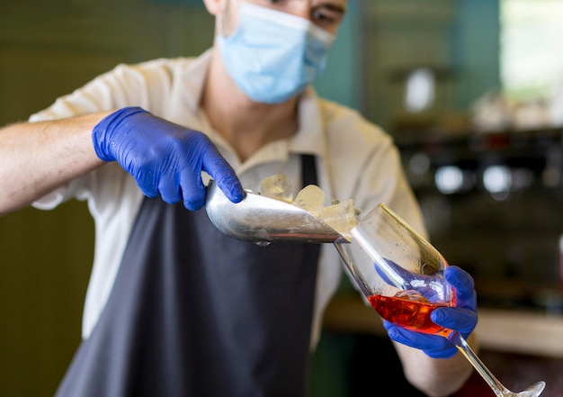 Close-up waiter with gloves preparing drink