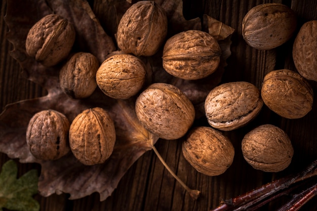 Free photo close up walnuts on wooden table with leaves