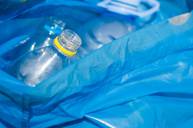 Close-up of waste plastic bottle in blue garbage bag