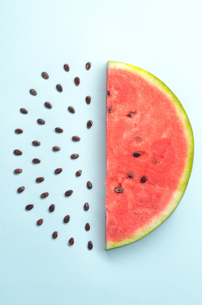 Close up of watemelon's red ripe slice and black stones isolated over blue