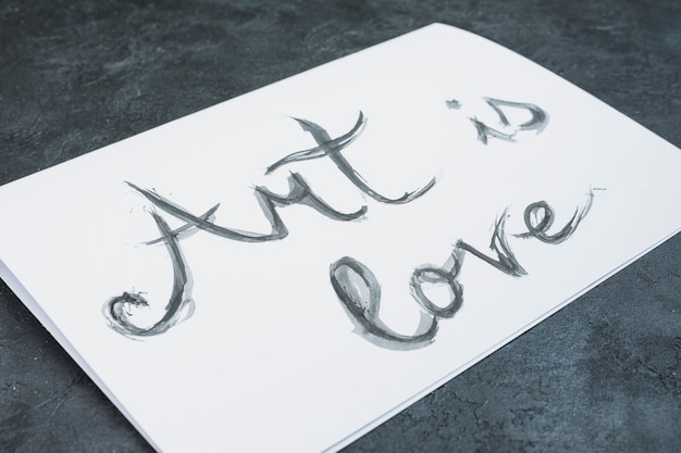 Free Photo close-up of watercolor hand drawn 'art is love' text on white paper