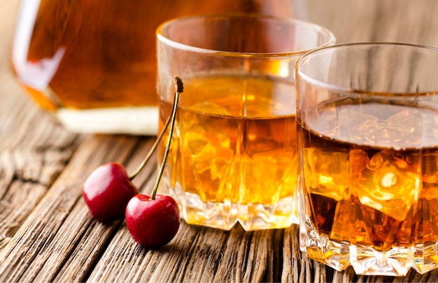 Close-up whiskey glasses with ice and cherries