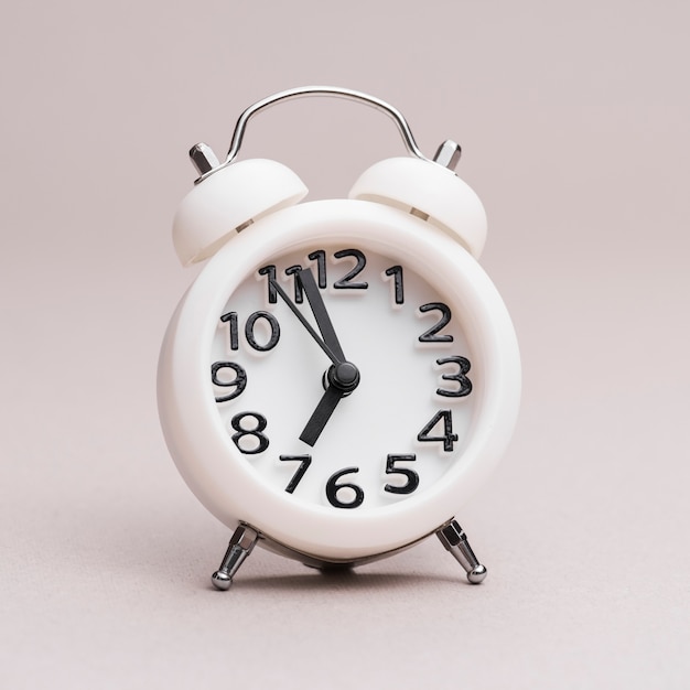 Close-up of white alarm clock on colored backdrop