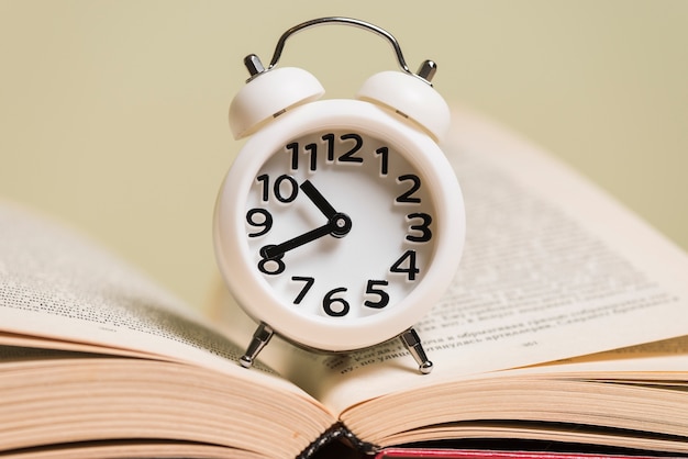 Free Photo close-up of white alarm clock on an open book