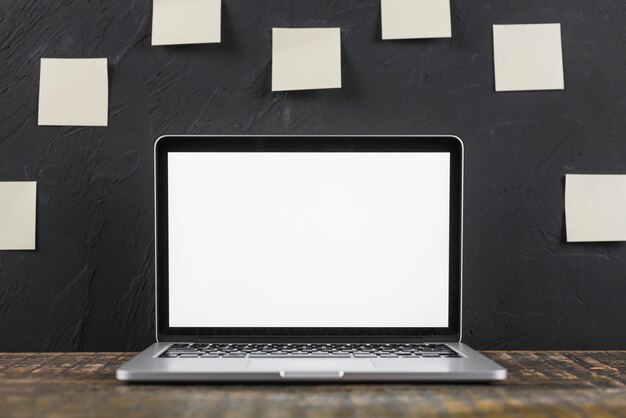 Close-up of a white blank screen laptop on wooden table