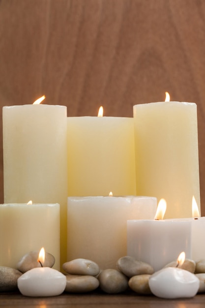 Close- up of white candles and pebbles stone on wood