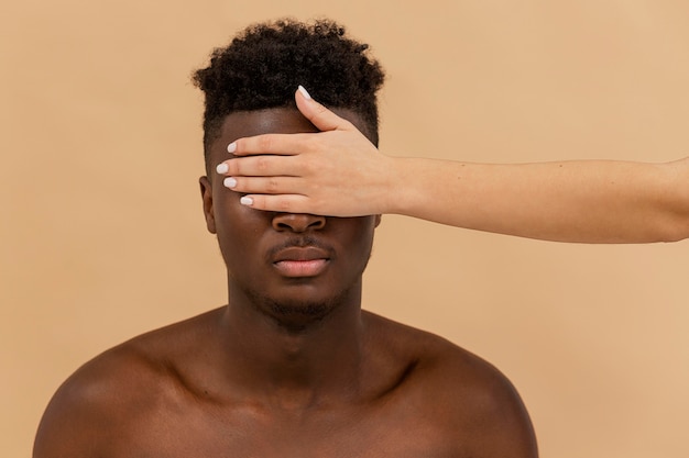 Free photo close-up white hand covering black man eyes