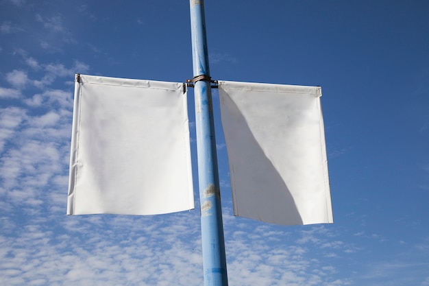 Free Photo close-up of white lamp post banner poster against blue sky