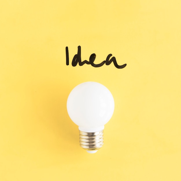 Free Photo close-up of a white light bulb with idea word on yellow background