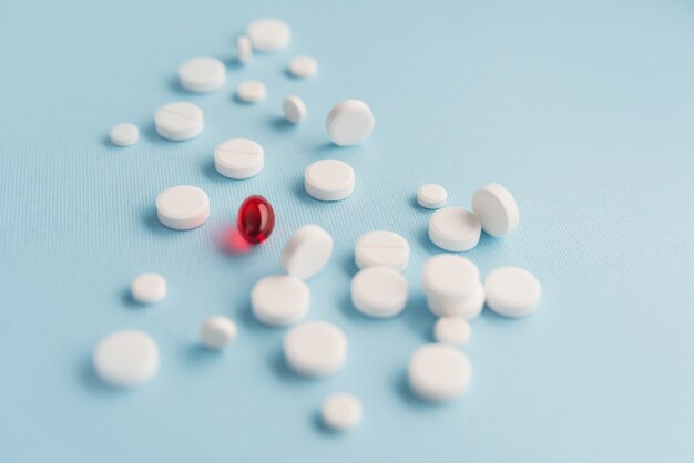 Close up of white tablets with one red capsule