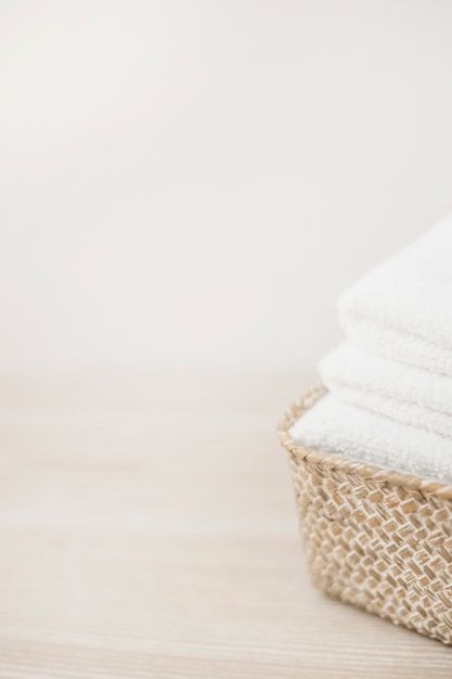 Free Photo close-up of white towels in basket on wooden tabletop