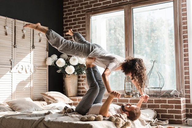 Close-up of a woman balancing man's feet on bed at home