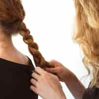 Free photo close-up of woman braiding sister's hair against white background