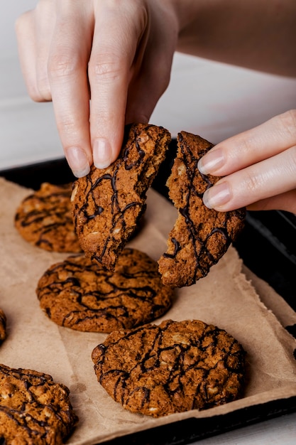 Free photo close up woman breaking delicious cookies