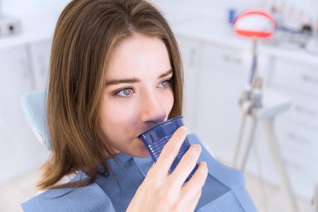 Free photo close-up of a woman in dental chair take glass of water