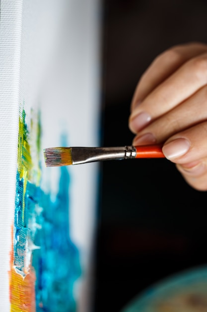 Free photo close up of woman drawing with oil paints on canvas