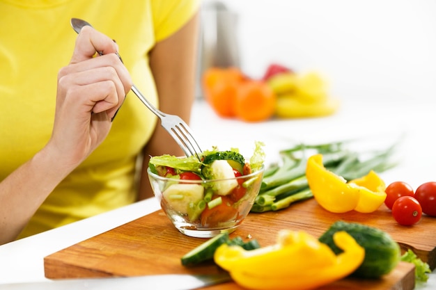 Close-up of a woman eating salad in the kitchen