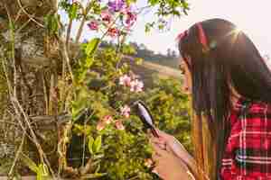 Free photo close-up of a woman examining flower through magnifying glass