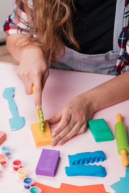 Close-up of woman hand cutting colorful clay on table