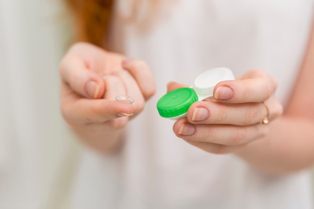 Close-up of woman hand holding contact lens and it's container