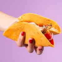 Free photo close-up woman holding burrito with purple background