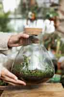 Free photo close-up woman holding jar with plants