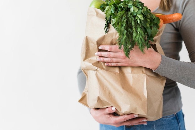 Free photo close-up woman holding paper bag with vegetables