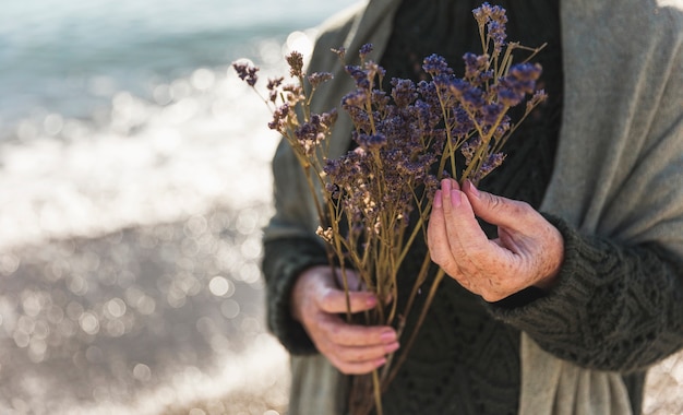 Free photo close-up woman holding purple flowers outdoors