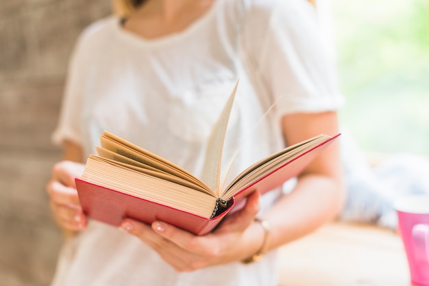 Close-up of woman holding red cover book in hands