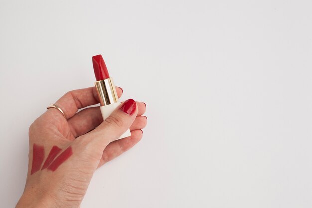 Close-up woman holding red lipstick